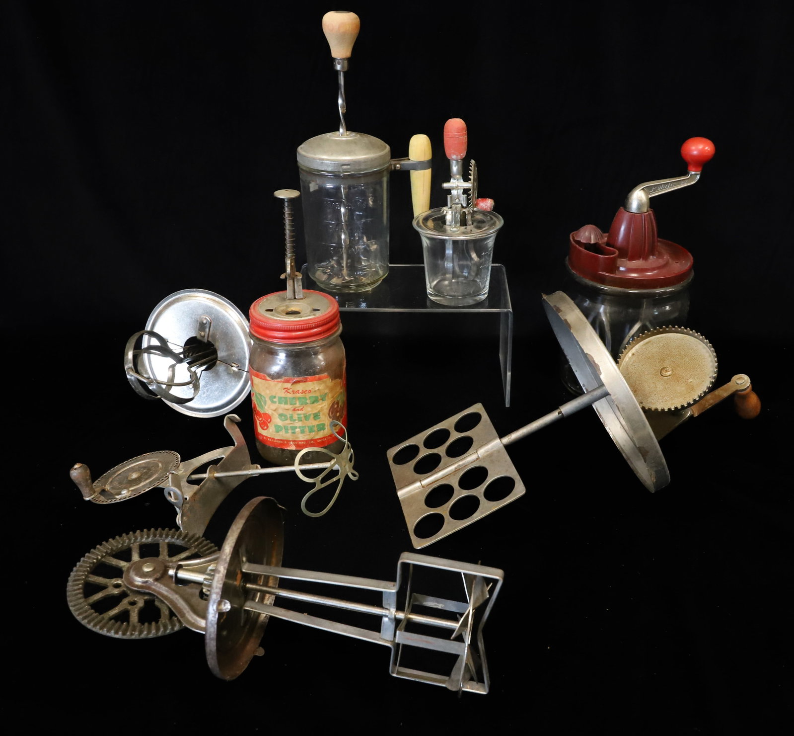 LOT OF VINTAGE KITCHEN MIXERS AND MORE: INCLUDING: CHILD'S BEATER MRKD. "BETTY TOPLIN" IN BOTTOM. 6" H. EMBOSSED GLASS BEATER WITH WOODEN HANDLE. "CHERRY AND OLIVE PITTER" W/ ORIGINAL LABEL. "RUHRFIX" BEATER WITH EMBOSSED GLASS BASE AND