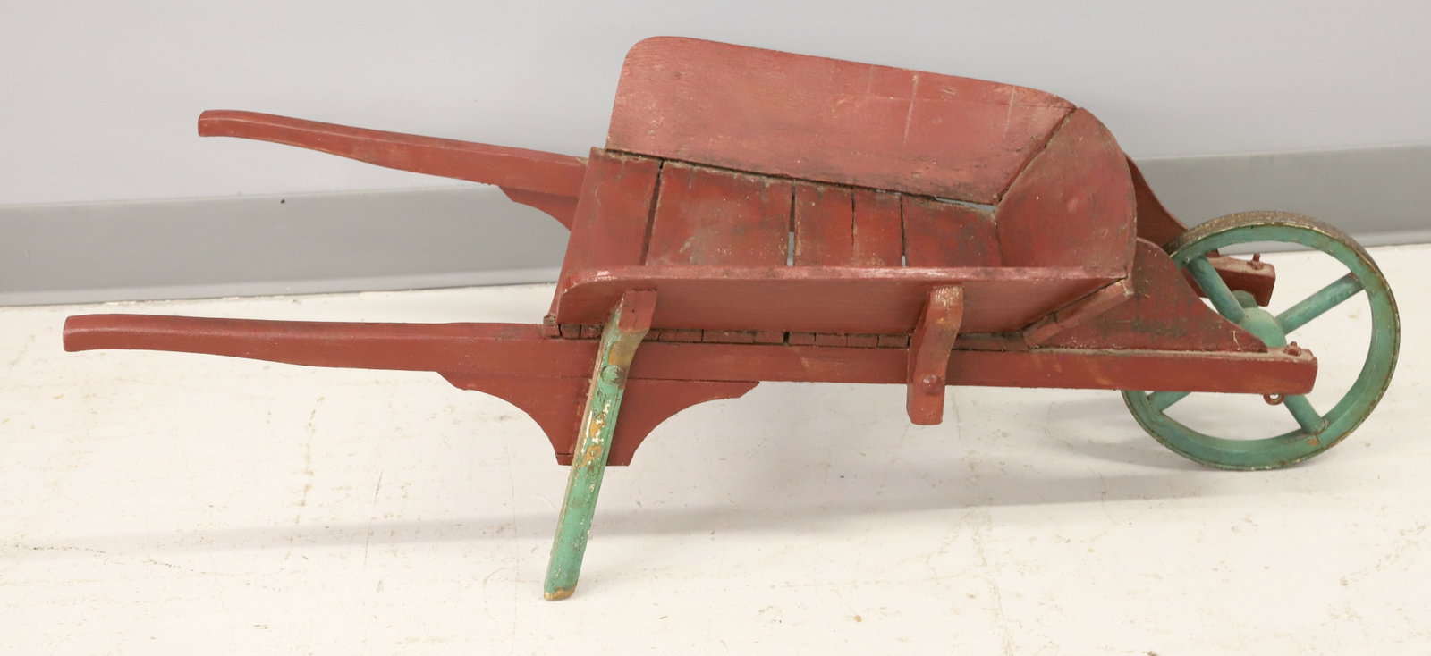 PAINTED CHILD'S WHEELBARROW: RED / GREEN PAINTED SURFACE. MRKD. ON BOTTOM "THE CANADIAN WAGON AND NOVELTY CO. PRESTON, ONTARIO" 38" X 16". PLEASE READ CAREFULLY - ITEMS MUST BE PAID FOR THROUGH LIVE AUCTIONEERS OR WITH CASH OR CH