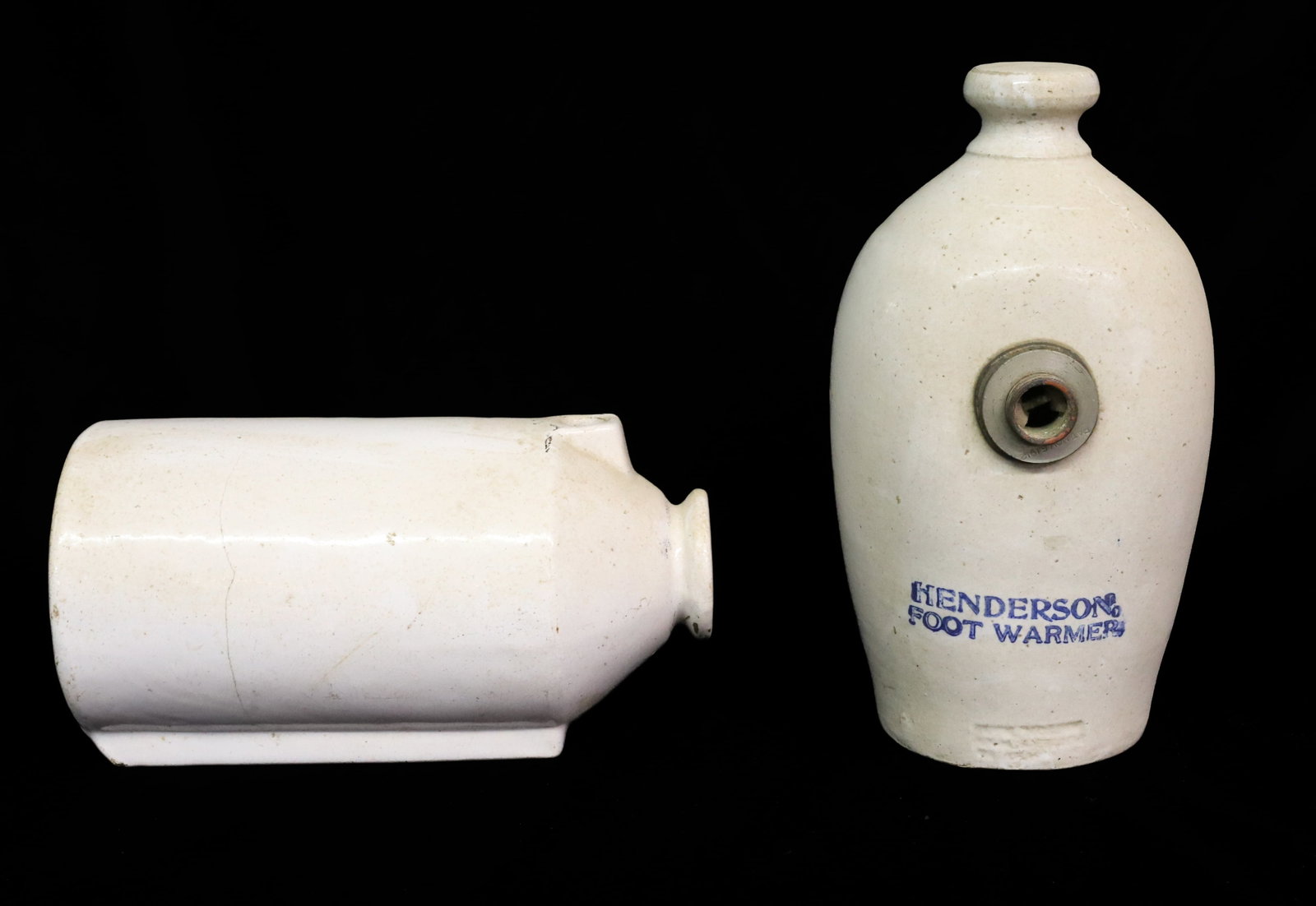 (2) STONEWARE FOOT WARMERS: WHITE GLAZE. ONE STAMPED "HENDERSON FOOT WARMER" IN BLUE. ILLEGIBLE STAMPED IMPRESSION BELOW. 11" L. WITH, CYLINDRICAL SHAPED WARMER UNMARKED. 10 1/4" L. PLEASE READ CAREFULLY - ITEMS MUST BE PAID