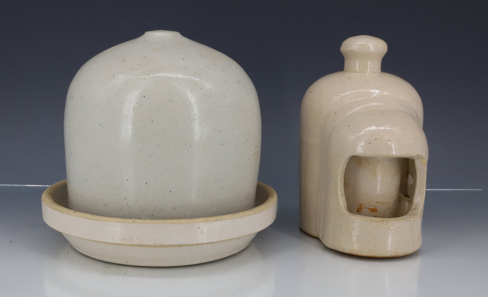(2) SMALL STONEWARE CHICK WATERERS: WHITE GLAZE. TWO-PIECE EXAMPLE HAS SAUCER AND DOMED TOP WITH HOLE IN BOTTOM EDGE. 6 1/2" X 7 1/4". WITH, SMALL EXAMPLE WITH KNOB TOP. 6 1/4" X 5". PLEASE READ CAREFULLY - ITEMS MUST BE PAID FOR THROUG