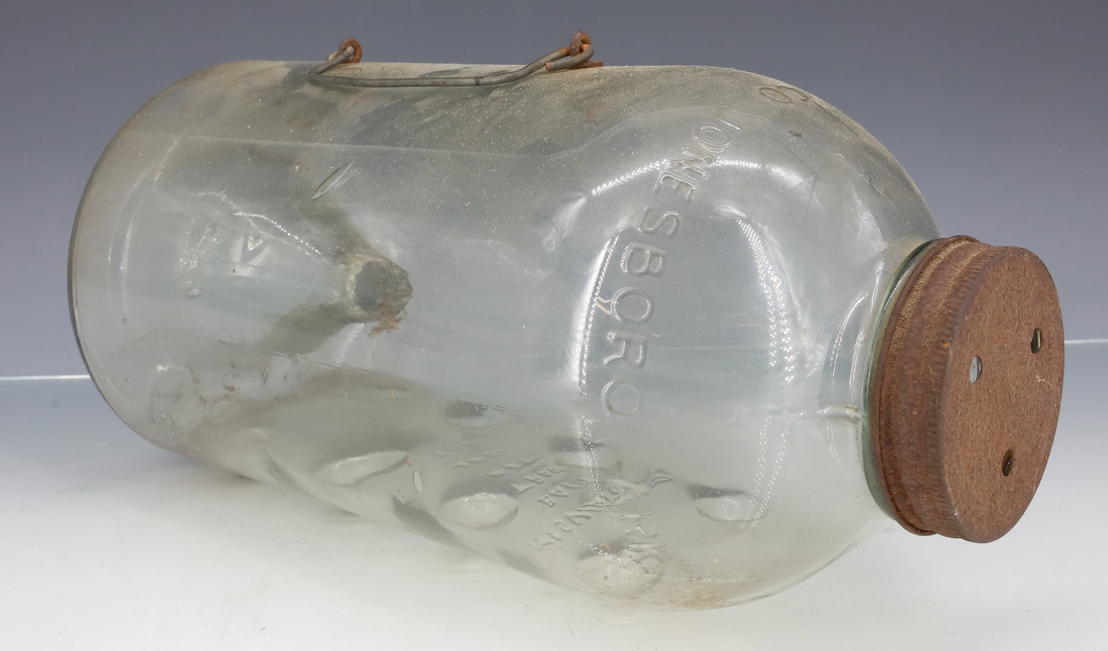 GLASS "MC SWAIN JR. BAIT TRAP": EMBOSSED GLASS WITH WIRE AND TIN LID. MRKD. "MCSWAIN GLASS CO., JONESBORO ARK...ROACHES, MINNOWS". 12" L. PLEASE READ CAREFULLY - ITEMS MUST BE PAID FOR THROUGH LIVE AUCTIONEERS OR WITH CASH OR CHECK 