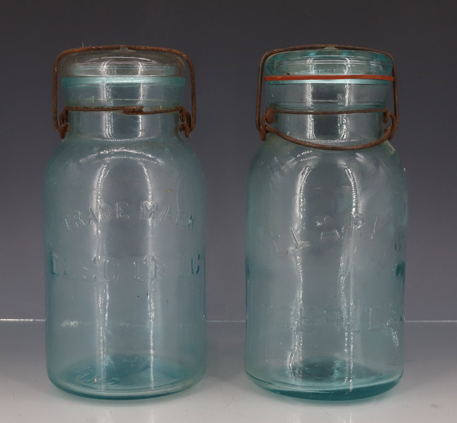 ELECTRIC AND "CLARK'S PEERLESS" FRUIT JARS: TWO AQUA JARS. "TRADEMARK ELECTRIC, SALEM, NJ" WITH WIRE CLOSURE AND GLASS LID. 8" H. "CLARK'S PEERLESS" WITH WIRE CLOSURE AND GLASS LID. 7 3/4" TOTAL HEIGHT. PLEASE READ CAREFULLY - ITEMS MUST BE