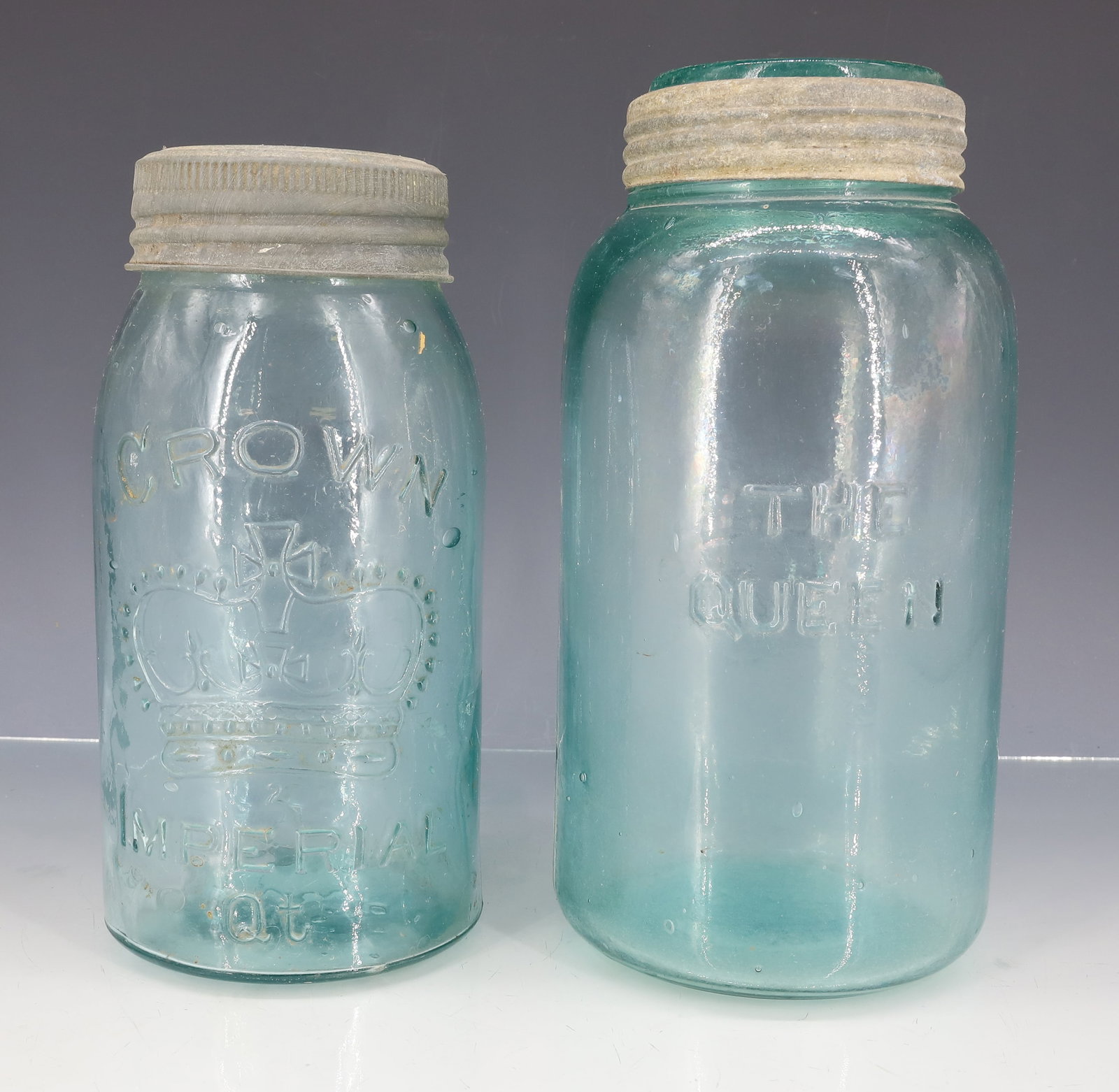 CROWN AND "THE QUEEN" FRUIT JARS: TWO AQUA JARS. "CROWN IMPERIAL QT" WITH LARGE CROWN ON FRONT. GLASS INSERT LID WITH CROWN. 8" TOTAL HEIGHT. WITH, "THE QUEEN". EMBOSSED MONOGRAM ON OPPOSITE SIDE. BOTTOM MRKD. PAT. NOV. 1869, #376.