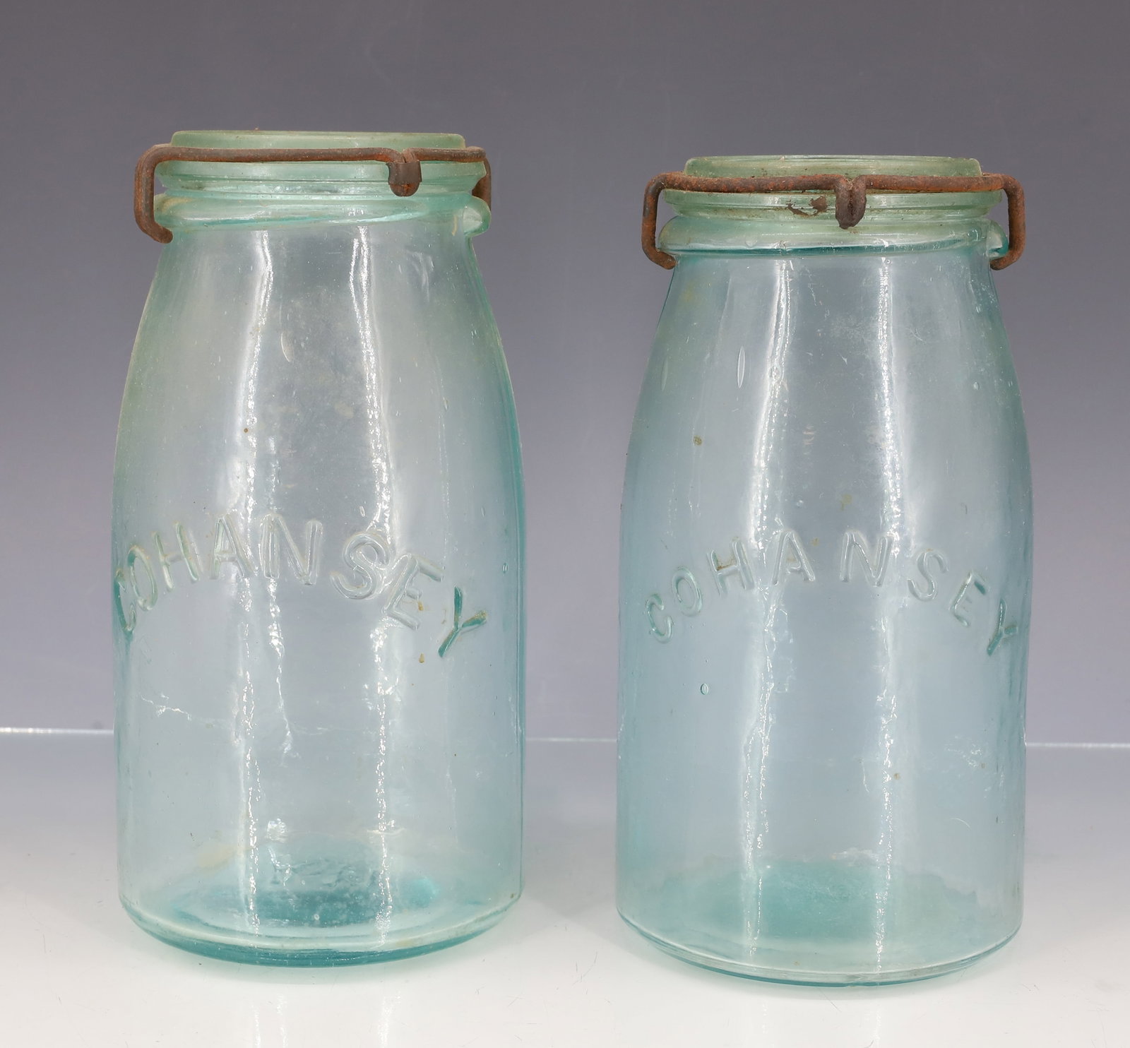 (2) "COHANSEY" AQUA FRUIT JARS: DIFFERENT SIZE EMBOSSED NAME ON FRONTS. ONE MRKD. A11 AND OTHER MRKD. 58 ON BOTTOMS. GLASS LIDS WITH WIRE CLOSURES. "PATENTED JANUARY 18 1876" ON BOTH LIDS. 7 3/8" HEIGHTS. PLEASE READ CAREFULLY -