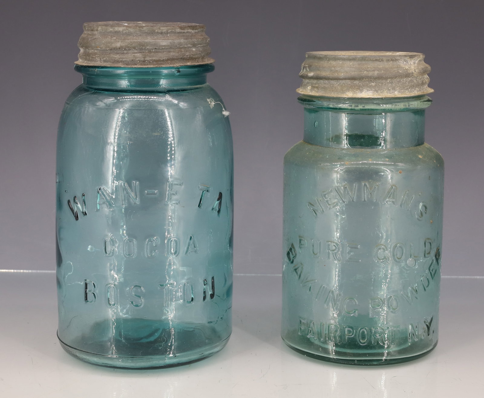 NEWMAN'S BAKING POWDER AND WAN-E TA COCOA JARS: AQUA JARS WITH ZINC LIDS. "NEWMAN'S PURE GOLD BAKING POWDER, FAIRPORT, N.Y." 6 1/2" H. WITH, "WAN-E TA COCOA BOSTON" 7 1/8" H. PLEASE READ CAREFULLY - ITEMS MUST BE PAID FOR THROUGH LIVE AUCTIONEERS