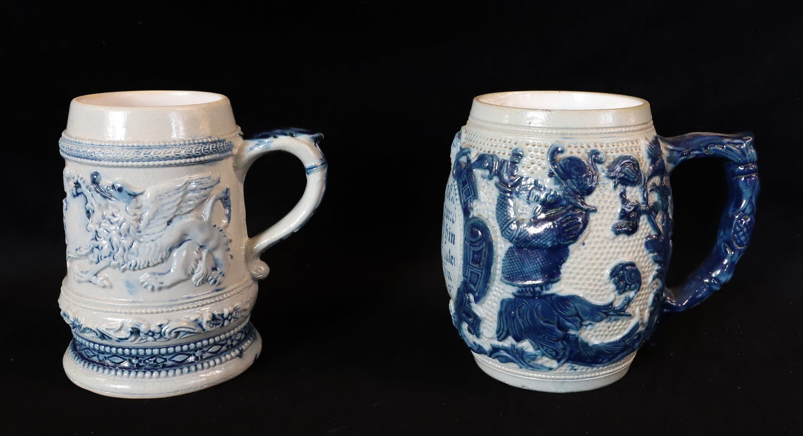 (2) WHITE'S UTICA STONEWARE MUGS: SMALLER HAS WINGED BEAST ON ONE SIDE WITH VERSE ON OPPOSITE. MRKD. 35 ON BOTTOM. 4 3/4" H. OTHER, DONE IN DARKER BLUE WITH VERSE OPPOSITE THE HANDLE. UNMARKED. 4 3/4" H. PLEASE READ CAREFULLY - ITEMS 