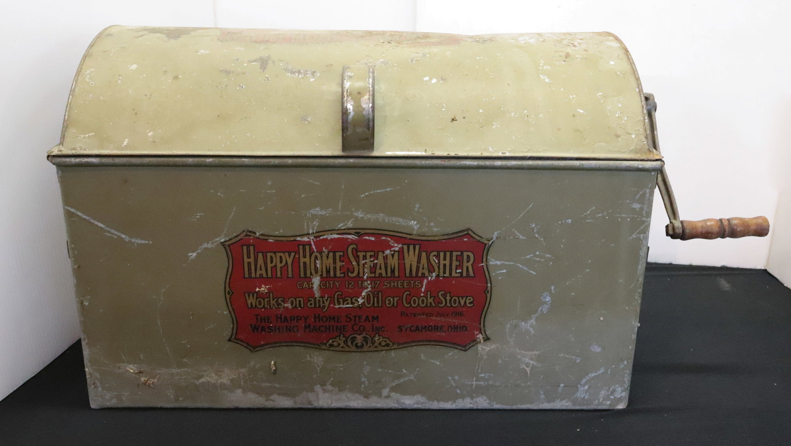 HAPPY HOME STEAM WASHER: PAINTED METAL WASHING MACHINE FOR ON TOP OF STOVE. ORIGINAL LABEL ON FRONT AND TOP. LIFT-OFF LID AND SIDE CRANK. 21 1/2" L. PLEASE READ CAREFULLY - ITEMS MUST BE PAID FOR THROUGH LIVE AUCTIONEERS OR W
