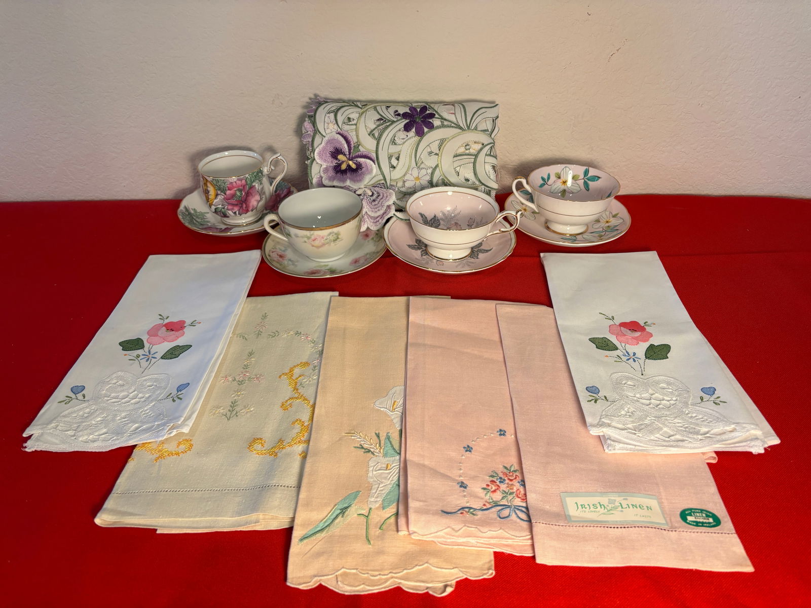 11 Piece Teatime Setting Lot: Embroidered Tablecloth 32"x33". No holes. Some small stains. 6 Tea Towels. Peach & Beige with smallstains. Royal Grafton, Royal Albert, Paragon fine bone china tea cups. Austria teacup. No chips orrep