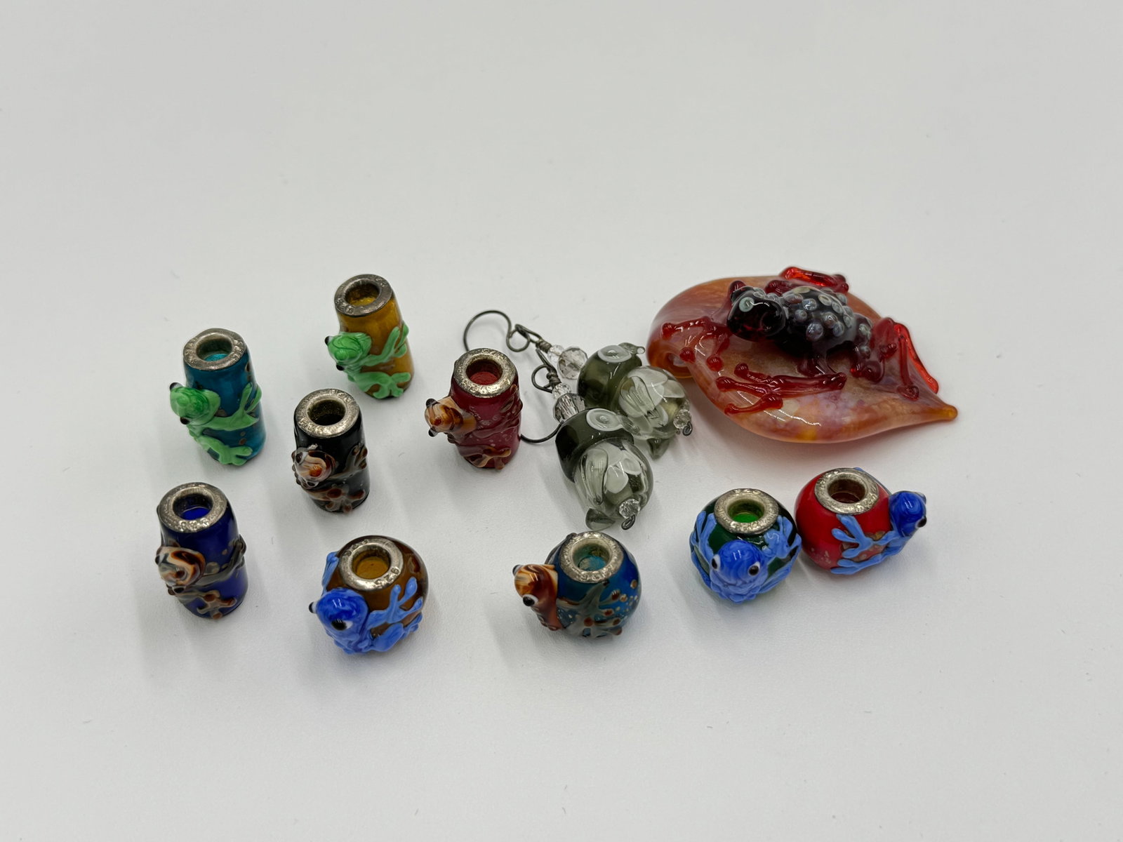 Amazing lot of sterling silver glass charms/pendants and more: Amazing lot of sterling silver glass charms/pendants and more. Including 9 charms/pendants marked 925, glass larger frog pendant and earrings. SEE PICTURES FOR MORE DETAIL AS THEY ARE THE BEST DESCRIP