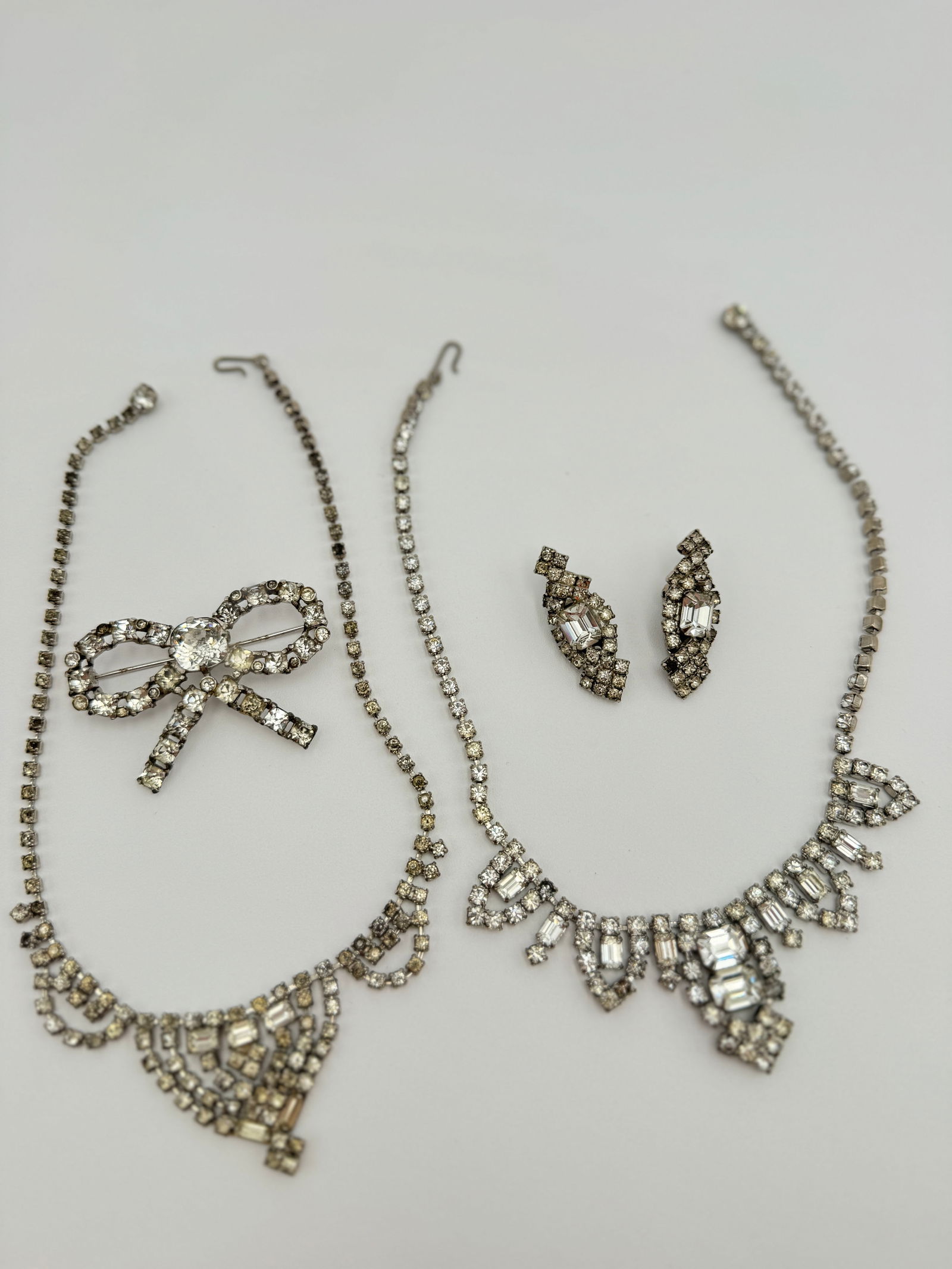 Collection of 1950’s mid century rhinestones jewelry: Collection of 1950’s mid century rhinestones jewelry. Including 2 necklaces, earrings and nice bow coro signed brooch. No stones missing, some stones might be yellowish. See pictures for more detail