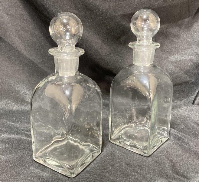Pair of Glass Decanters: Pair of glass decanters with bubble stoppers. Measures 11"H x 3 3/4" square. In good condition with chipping to bottom of stoppers. Shipping Available.