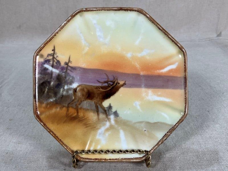 Nippon Trivet with Hand Painted Elk: Nippon trivet with a hand-painted elk and a forested background, Morimura Brothers mark. Measures approx. 5 3/4''. Good condition with some light wear.