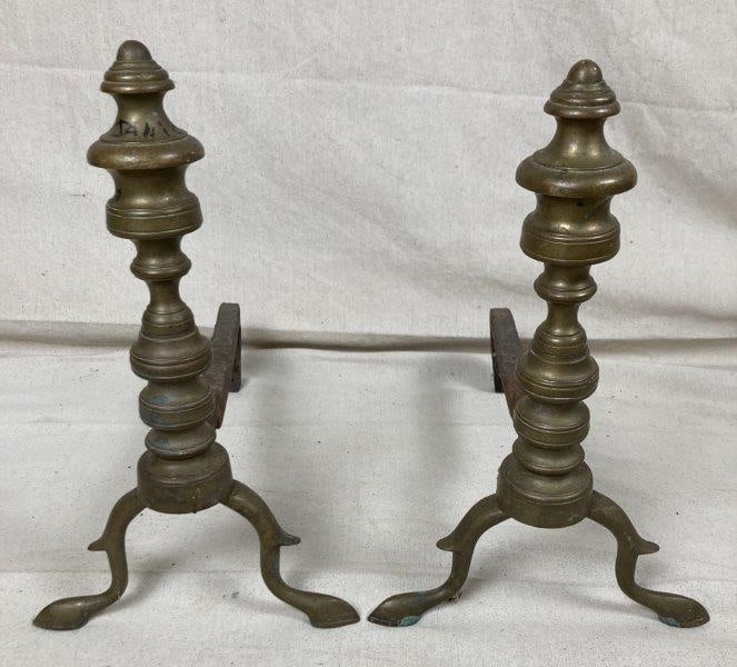 Pair of Early Brass Andirons: Featuring classic form with graceful silhouettes, these early brass andirons showcase a warm, aged patina. Measures approx. 14''T x 8''W 17''D. Some wear. Shipping Available.