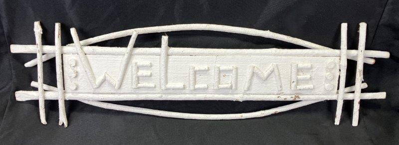 Folk Art Twig Welcome Sign: Charming handmade sign with twig lettering mounted on a painted white board. Rustic and inviting with folk art appeal. Measures approximately 12'' x 30''. Good condition with light wear. Shipping