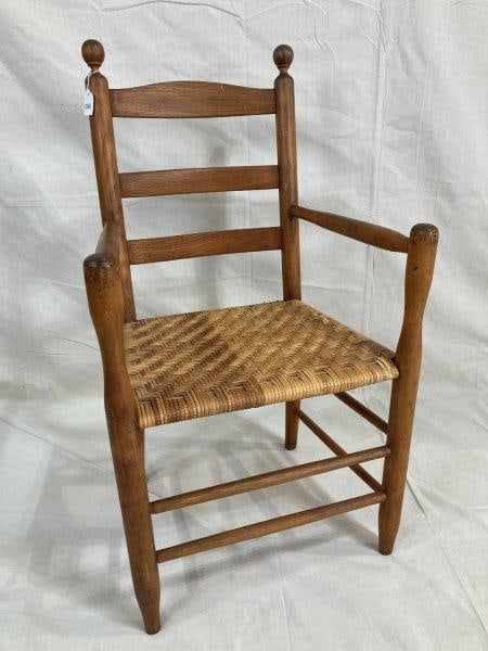 Southern Country Armchair: Traditional country armchair featuring a shaped top splat, woven seat, and slightly turned arm posts. Measures approximately 38''H x 22''W x 16''D; seat height 17''. Good condition with minor wear. Sh