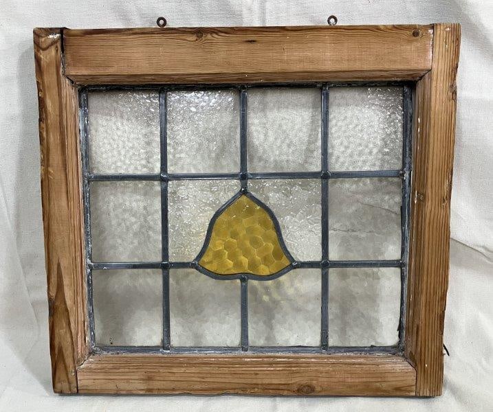 Stained Glass Window with Bell Motif: Colorful stained glass window featuring a central bell design, housed in a rustic yellow pine frame. A charming decorative element with vintage character. Measures 19''H x 21''W. Some loss to frame an