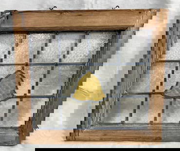 Stained Glass Window with Bell Motif: Colorful stained glass window featuring a central bell design, housed in a rustic yellow pine frame. A charming decorative element with vintage character. Measures 19''H x 21''W. Some loss to frame