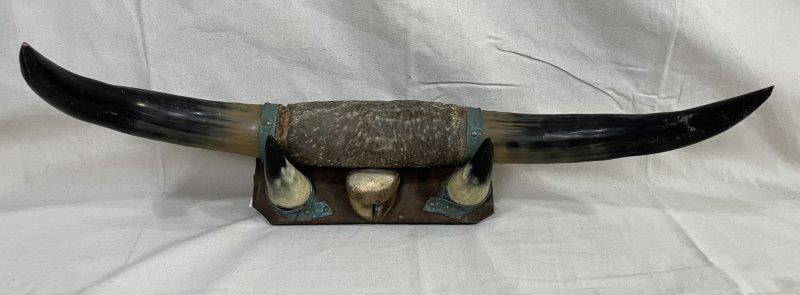Mounted Steer Horns: Striking display featuring two sets of mounted steer horns on a leather-wrapped board, creating a bold and rustic statement piece. Measures approx. 6''H x 32''W. Displays loss to leather and to the