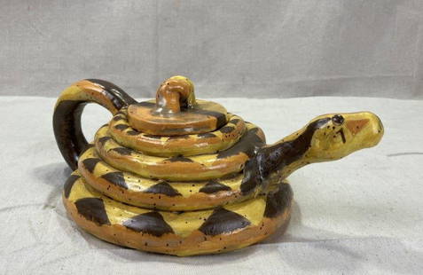 Folk Art Snake Teapot: Whimsical hand-crafted teapot in the form of a coiled snake, polychromed in yellow, brown, and orange tones. Signed Cati on the base. Measures approximately 4 1/2''H x 10''L. Good condition with