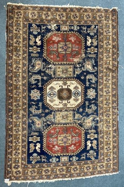 Hand-Knotted Persian Rug: Beautifully woven Persian rug featuring intricate decoration in rich tones of blue, red, and tan, with animal motifs around the border. Measures approximately 56'' x 83''. Wear to the binding and scat