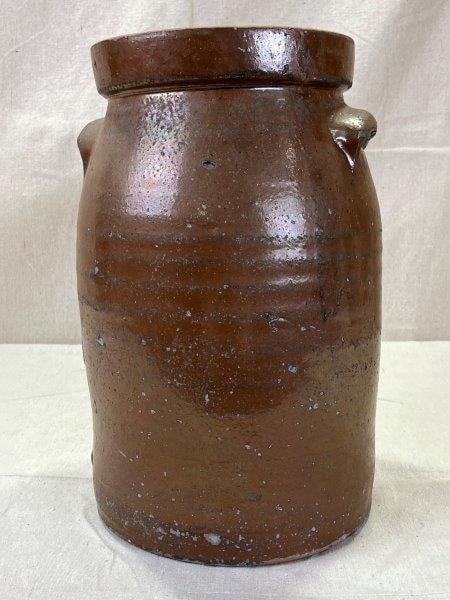 Southern Stoneware Crock: Of classic cylindrical form, this utilitarian stoneware crock features a rich, brown glaze with subtle mottling and depth. Twin applied lug handles are neatly affixed at the shoulders, showcasing the