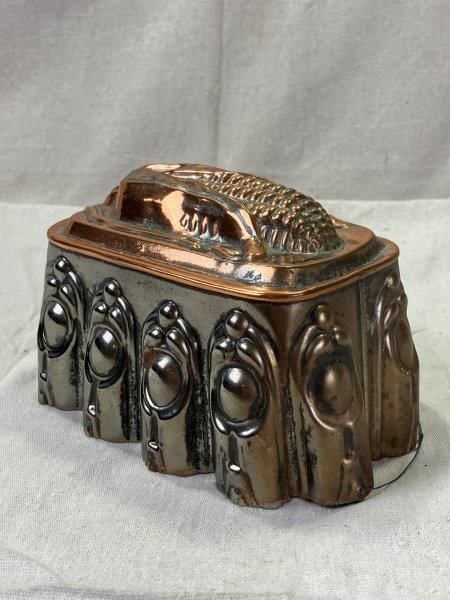 Tin Mold with Corn Decoration and Copper Finish: Pressed in relief with a detailed corn motif, this decorative tin mold features a warm copper-colored finish that highlights its textured surface. Mold measures 4 1/4"T x 7 3/8"W x 4 3/4"D. In good co