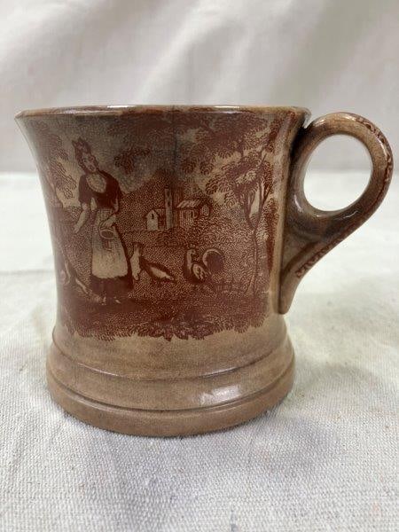 19th-Century Ironstone Transferware Shaving Mug: Of traditional form with distinctive â€œOâ€-shaped handle, this ironstone shaving mug features a transfer-printed pastoral scene depicting a woman feeding turkeys on a