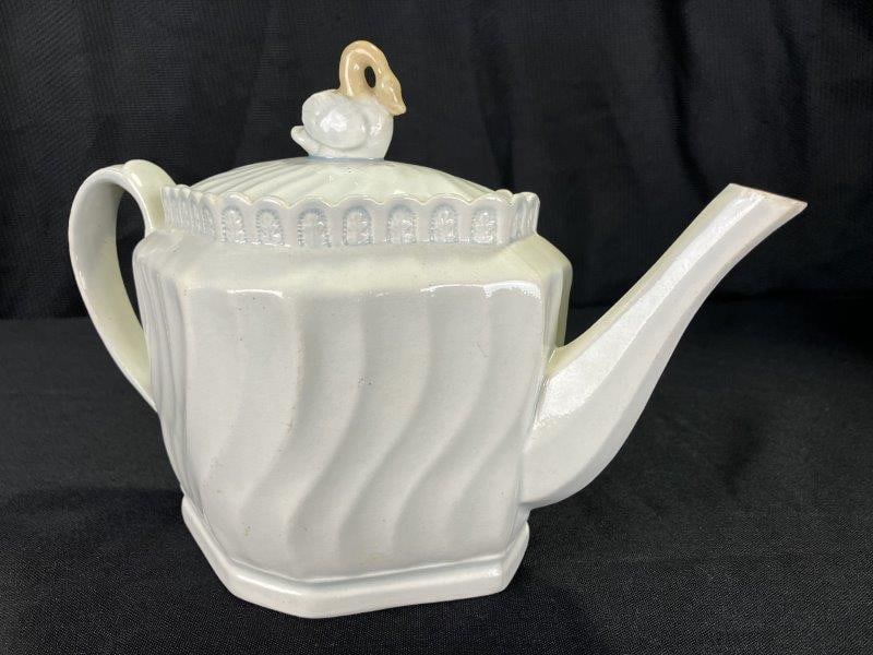 Pearlware Swan Motif Teapot: Decorated with a vegetal border and soft blue accents on a pale body, this charming teapot features an elegant swan finial in white and tan glaze. Measures approximately 7 1/2''T x 10''W x 5 1/2''D. T