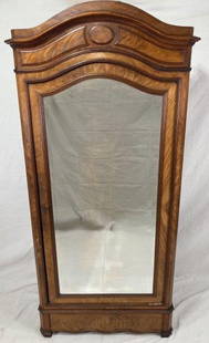 19th Century French Walnut Linen Press: A refined example with gracefully curved crown and carved central medallion, the mirrored door framed by subtle molding details. Rich walnut grain throughout with interior fitted for storage. Approx.