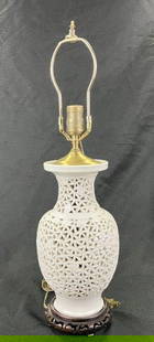 Chinese Pierced Porcelain Lamp: A decorative Chinese porcelain lamp featuring finely painted floral motif patterning and delicately pierced openings throughout the body. Mounted with brass fittings, the lamp combines elegant craftsm