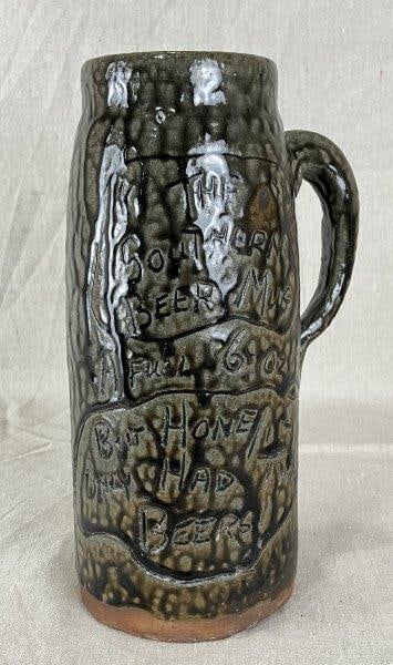 Cleater Meaders Alkaline Glaze Stoneware Mug: Robust stoneware mug with a runny alkaline glaze, inscribed with the humorous phrases "The Southern Beer Mug", "A Full 6 oz", and "But Home Only Had Beer". Created by renowned Georgia potter Cleater M