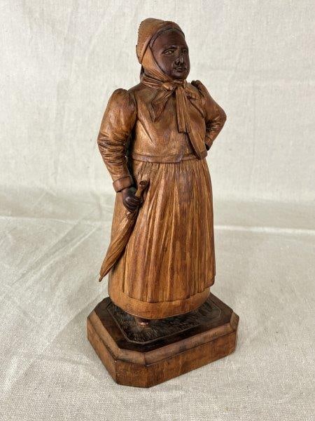 Carved Female Figure: Beautifully carved folk art female figure with a detailed face and intricately rendered clothing, finished in a warm patina. Initialed B.B. on the bottom. Measures approximately 10 1/2'' H x 4 5/8'' W
