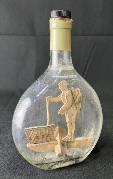 Folk Art Bottle: Whimsical folk art bottle featuring a hand-painted rendition of a man at work, crafted with charming detail and expressive character. Measures approximately 9 1/4" H x 6" W x 2" D. Age-appropriate wea