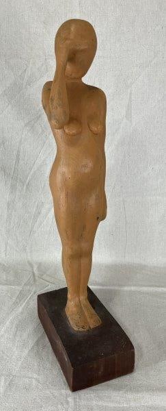 Hand Carved Female Nude Figure: Striking hand-carved female nude with sculpted body features, depicted with one hand covering her eyes in a graceful, emotive pose. Measures approximately 23 1/4'' H x 4 5/8'' W x 9'' D. Good conditio