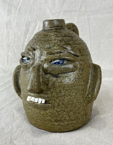 B.R. Holcomb Pottery Face Jug: Handsome southern face jug, runny green glaze with angry face and blue eyes. Signed Holcomb Measures approx. 8" H x 6 1/2" W x 6" D. Good condition.