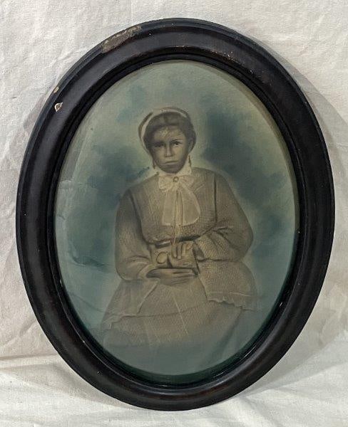 African American Oval Print with Convex Glass: Distinctive depiction of a seated African American woman with delicately rendered features, set against a rich grey and brushed blue background. Measures approximately 22 1/2" H x 16 3/8" W x 1" D. Fr