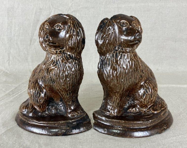 Pair Pottery Spaniels: Folk art pottery Spaniels finished in a warm brown glaze with molded fur detailing and expressive features. Measures approximately 7 1/4'' H x 6'' W x 2 1/2'' D. Good condition with light wear consist
