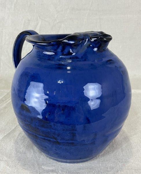 North Carolina Blue Pitcher: Attractive North Carolina pottery pitcher with a vibrant blue glaze and applied handle. Initialed W.C. on the bottom, indicating the maker. Measures approximately 7 1/2'' H x 5 1/2'' W x 8'' D. Good c