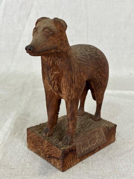 Carved Dog Figure Butch: Beautifully carved wooden dog figure with detailed fur texture and an expressive face. Labeled Butch and dated 1959, Measures approximately 6'' H x 5'' W x 2 3/8'' D. Good condition.