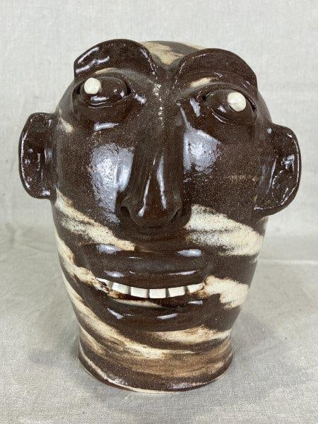 Marvin Bailey Swirl Wig Stand: Folk art face wig stand by potter Marvin Bailey, crafted from swirled clay with expressive white-painted teeth and eyes. Measures approximately 8 1/2'' H x 6 1/2'' W x 6'' D. Good condition.