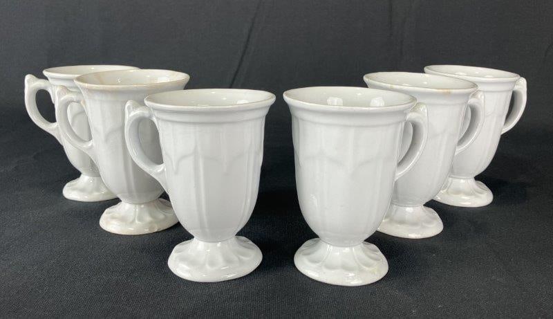 Six White Ironstone Sydenham Syllabus Footed Cups: Set of six elegant white ironstone footed cups in the Sydenham Syllabus pattern, featuring rich forms with geometric fluted design. Each measures approximately 4" H x 3 3/8" W x 2 1/4" D. Some crazing