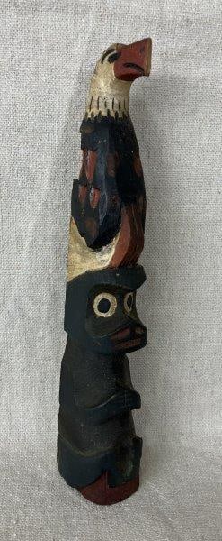 Miniature Carved Totem Pole: Carved wood depicting an eagle perched atop a bear, with painted finish. Measures approximately 8" H. Loss to wings.