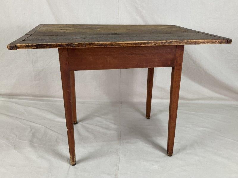 Painted Primitive Table: Weathered and worn surface with appealing age, featuring a three-board top and tapered legs. Some loss to one foot, consistent with age and use.
