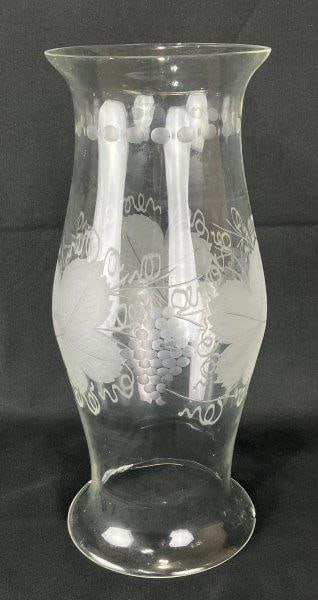 Etched Glass Grape and Vine Hurricane: A finely crafted glass hurricane with an intricately etched grape and vine motif encircling the body, graceful tapering form. Measures approximately 16 1/8" H x 6 5/8" in diameter. One small chip to b