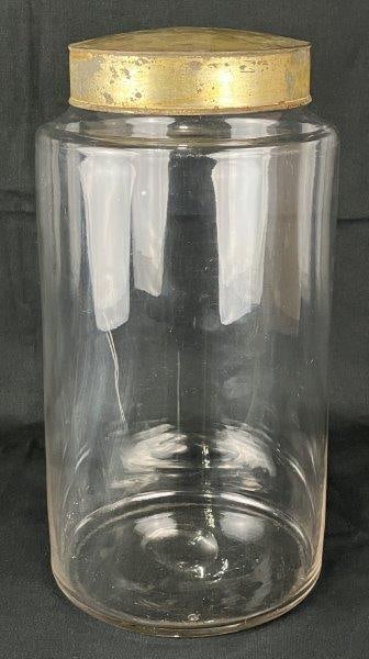 Country Store Glass Canister: Distinctive country store glass canister with brass-toned lid, nostalgic form ideal for storage. Measures approximately 14" H x 7" in diameter. Distinctive wear to lid; glass in good condition.