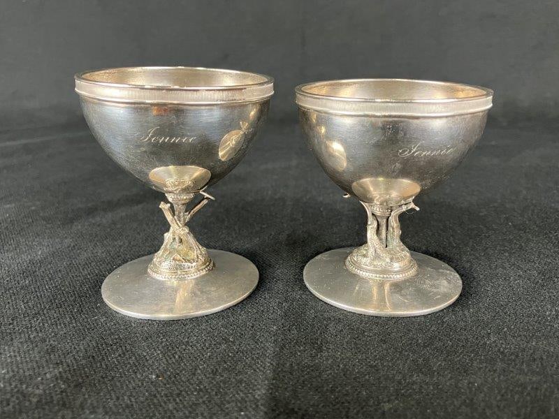 Coin Silver Egg Cup Pair: Cincinnati-made coin silver egg cups featuring ornate name engravings and figural tree-form bases with branching details. One measures approximately 2 1/2" H x 2 1/4" in diameter. Good condition with