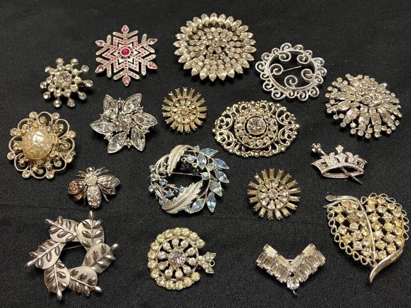 Seventeen Vintage Costume Brooches: A collection of seventeen vintage costume brooches, featuring clear and multicolored rhinestones in varied decorative forms. The largest measures 2 3/8". In good age-appropriate condition with minimal