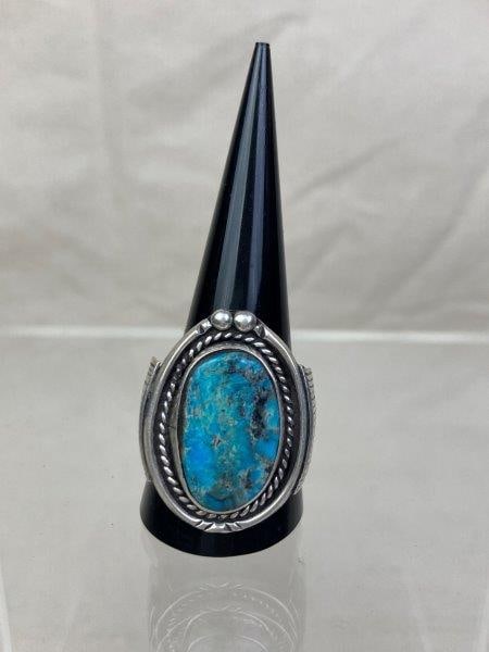 Native American Sterling Silver Ring with Turquoise: Unmarked sterling silver ring with turquoise stone, framed in a rope-twist bezel and accented with hand-engraved detailing. The face measures approximately 1 1/4". Ring size 11. In good condition with