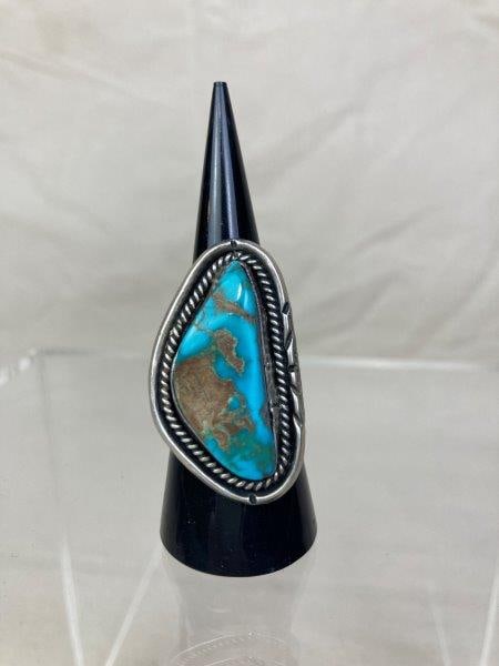 Native American Sterling Silver Turquoise Ring: Sterling silver ring featuring a single turquoise stone with natural matrix patterns, set within a rope-twist bezel and accented by hand-engraved detailing. Unmarked. The face measures approximately 1