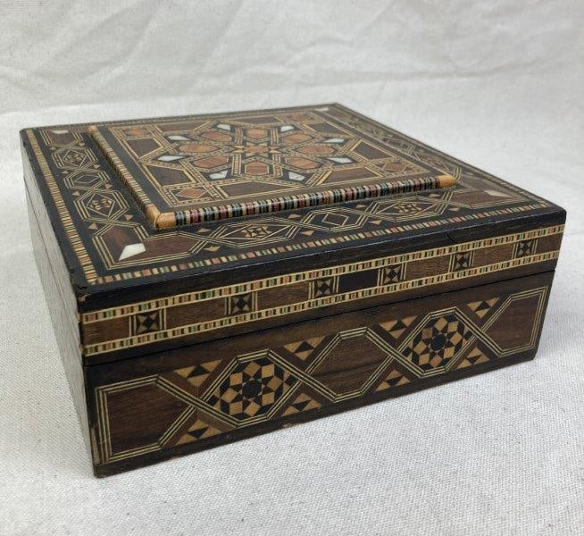 Geometric Mother of Pearl Inlaid Box: Beautifully detailed box featuring intricate geometric patterns with a central star motif on the lid. Felt-lined interior. Measures approximately 3'' H x 7 3/4'' W x 7 3/4'' D. Some light loss to inla